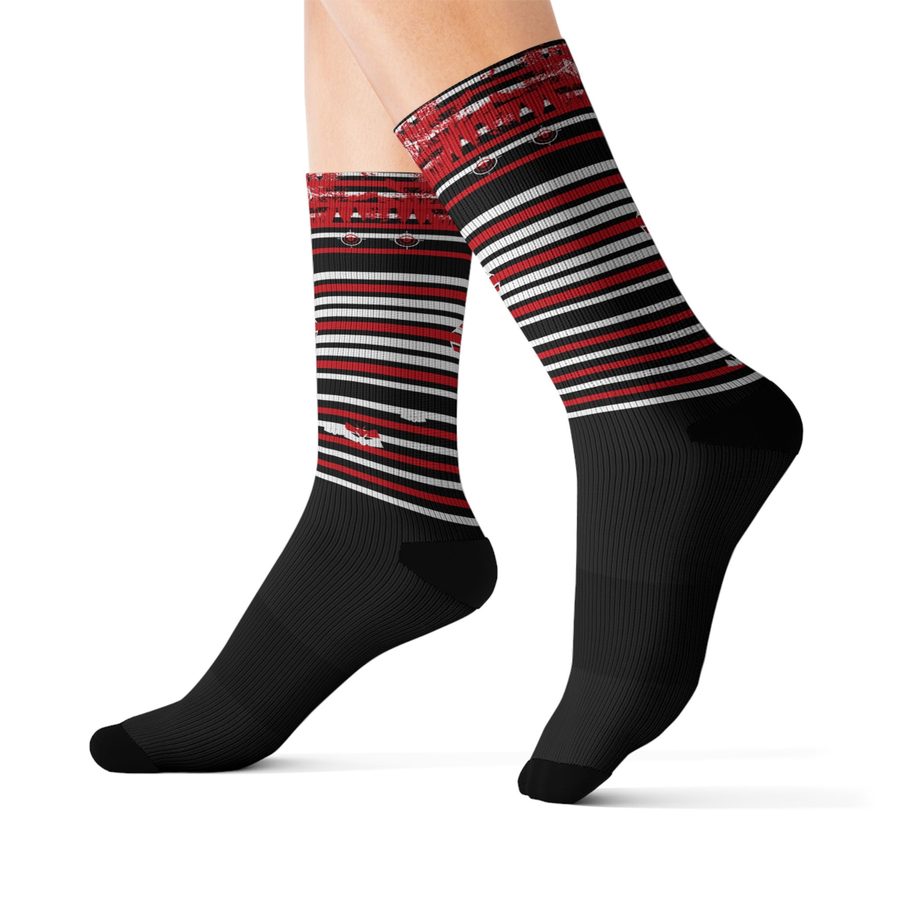 Static Moth Crew Socks, worn side view: black socks with red and white stripe bands and a winged moth emblem